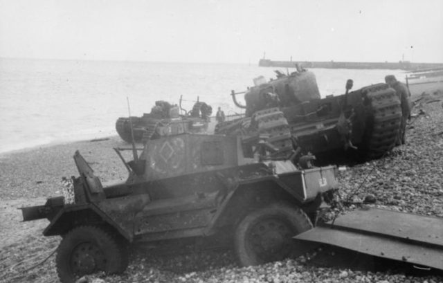 Daimler Dingo armoured car and two Churchill tanks bogged down on the shingle beach. The nearest Churchill tank has a flame thrower mounted in the hull, the rear tank has lost a track. Both have attachments to heighten their exhausts for wading through the surf. By Bundesarchiv, Bild 101I-362-2211-12 / Jörgensen / CC-BY-SA 3.0, CC BY-SA 3.0 de, https://commons.wikimedia.org/w/index.php?curid=5411278