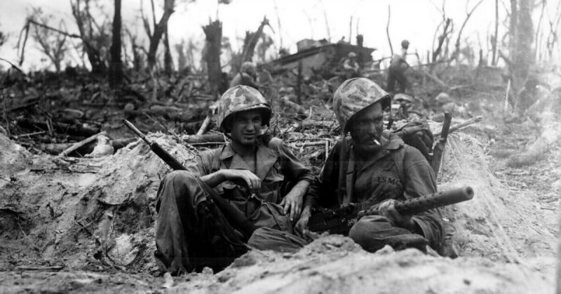 "Marine Pfc. Douglas Lightheart (right) cradles his 30-cal. machine gun in his lap, while he and his buddy Pfc. Gerald Churchby take time out for a cigarette, while mopping up the enemy on Peleliu Is." Cpl. H. H. Clements, September 14, 1944