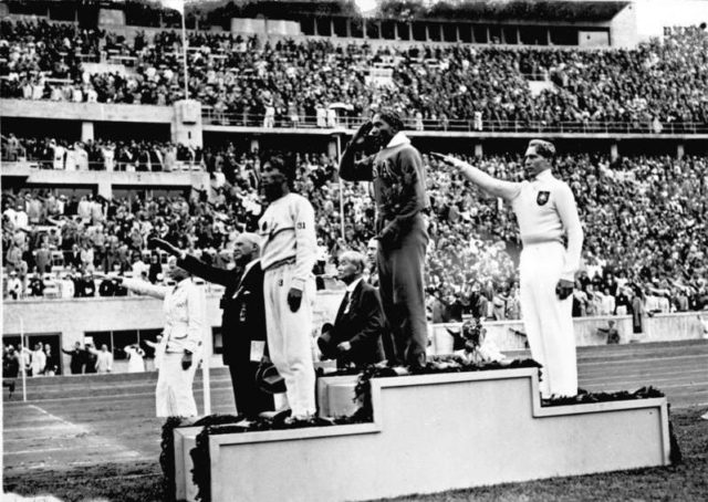 Jesse Owens on the podium after winning the long jump at the 1936 Summer Olympics. Photo Credit.