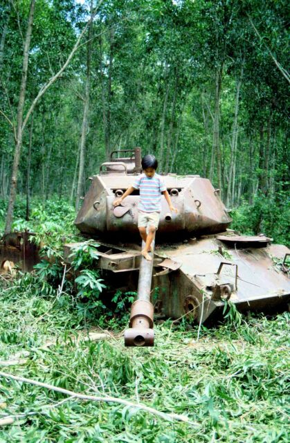 Young boy walking along the gun of a disabled M41 Walker Bulldog