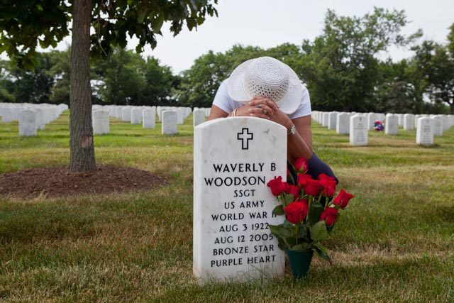 Woodson's grave at the Arlington National Cemetery, attended by his widow, Joann Image Source:
