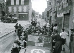 The Times correspondent Bob Cooper and other journalists are greeted by recently liberated villagers at Le Beny-Bocage