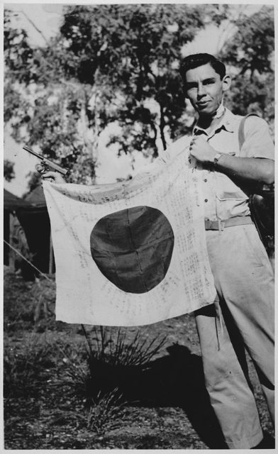 Lieutenant Woody J. Cochran, a Cherokee Indian and bomber pilot, holding up a captured Japanese flag and Nambu pistol during the New Guinea campaign on April 1, 1943.
