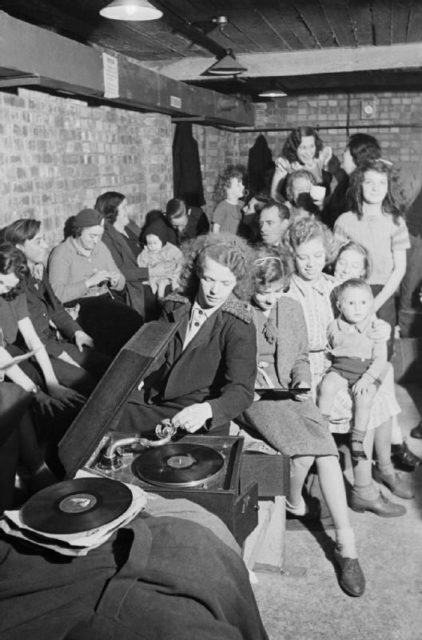 A young woman plays a gramophone in an air raid shelter in north London during 1940