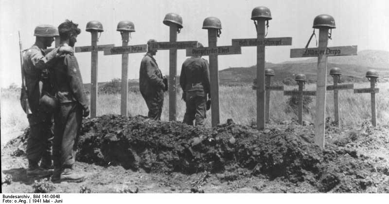 German soldiers pause before the graves of their fallen comrades. <a href=https://commons.wikimedia.org/wiki/Category:Images_from_the_German_Federal_Archive
>Photo Credit</a>
