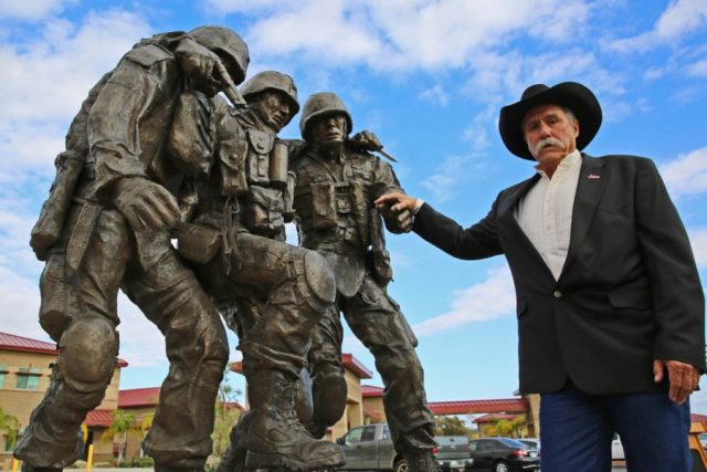 John Phelps poses with his creation after an unveiling ceremony Nov. 12, 2014, at the Wounded Warrior Battalion, Camp Pendleton, Calif.. The sculpture is based on the Operation Phantom Fury photograph 'Hell House' of then 1st Sgt. Bradley Kasal being carried out of a house by two lance corporals after a firefight where Kasal sustained life-threatening injuries. Shaltiel Dominguez/U.S. Marine Corps