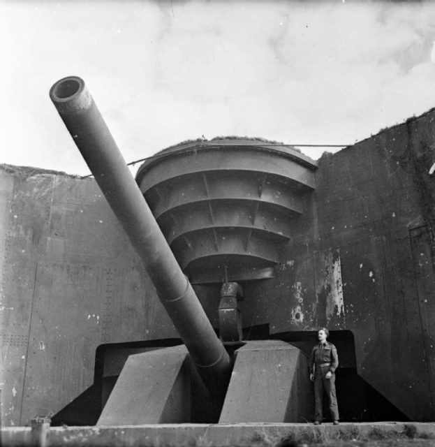 The British Army in North-west Europe 1944-45 A soldier poses next to one of the German coastal guns captured by the Canadians at Cap Gris Nez, 1 October 1944.