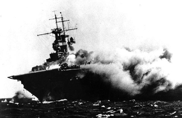 A port bow view of the ship shows her aflame and listing to starboard, 15 September 1942. Men on the flight deck desperately battle the spreading inferno. (U.S. Navy Photograph 80-G-16331, National Archives and Records Administration, Still Pictures Division, College Park, Md.)