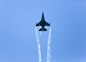 An F-16 fighter jet against a bright blue sky