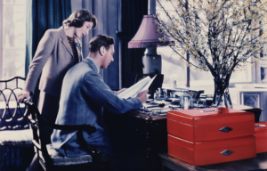 Princess Elizabeth looking over the shoulder of King George VI while he reads at a table