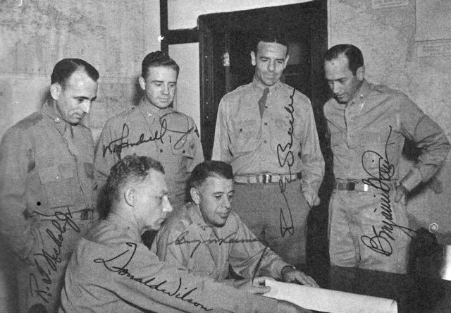 Kenney (center) surrounded by his staff.