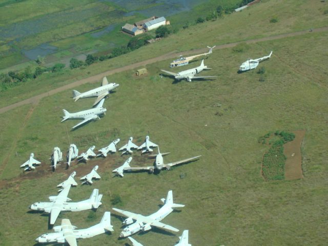 Photo above shows the Malagasy Air Force Boneyard in a bird’s eye view. This strange array reflects the switch that Madagascar made in its political preferences since its independence from French Colonial Rule in 1960. Aircraft from both the Western and the Eastern Military camps of the Cold war are peacefully united as “Brothers in Arms” on this boggy field just outside the International Airport of the Island´s Capital Antananarivo. But the reality was not so peaceful as in this picture and we would soon find out.