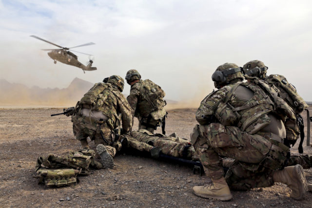 Modern military medic team prepare to move a simulated casualty to the evac helicopter during a training exercise.