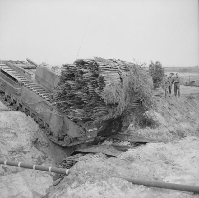 A Churchill AVRE, carrying a fascine, crosses a ditch using an already deployed fascine, (1943). Photo Credit.