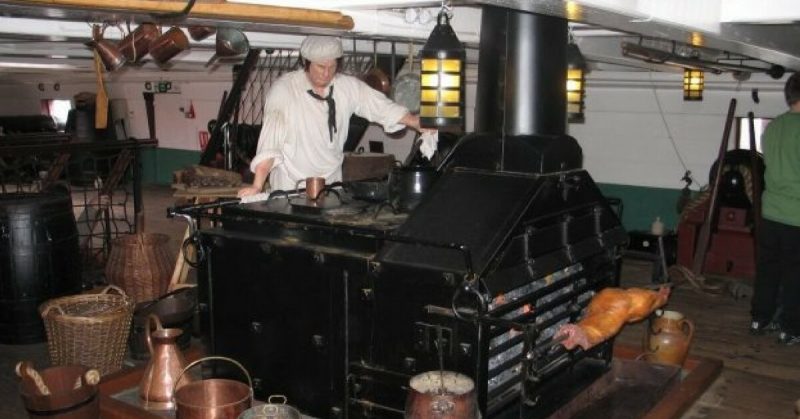 A sailor standing over a Royal Navy stove, onboard HMS Trincomalee. These stoves were designed to mass produce meals, being able to hold multiple cooking pots, and even a rotisserie. Ian Petticrew - CC BY-SA 3.0