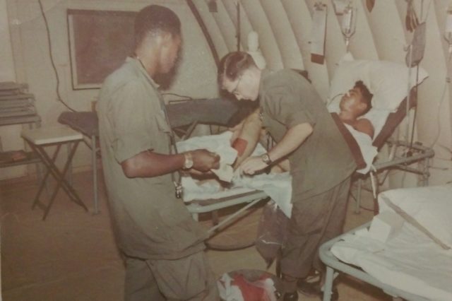 Roger Buchta (in Army uniform, right) served a year in Vietnam as a medic after he was drafted into the Army in 1966. He is pictured changing a bandage on a patient while stationed with the 18th Army Surgical Hospital in the Quang Tri Province of Vietnam. Courtesy of Roger Buchta.