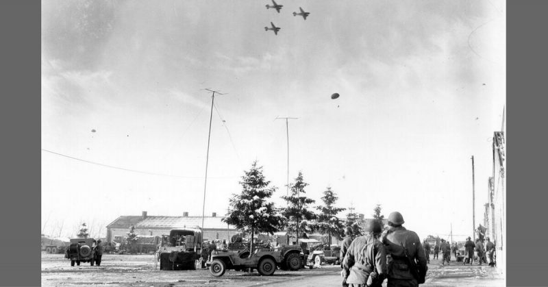 Troops of the 101st Airborne Division watch C-47s drop supplies to them during the siege. 