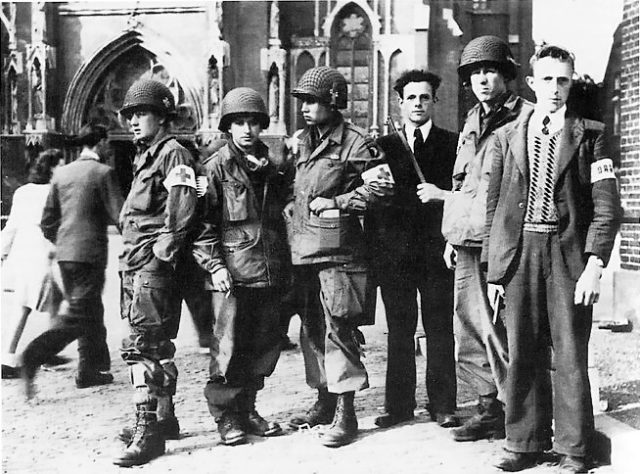 Members of the Dutch Resistance with troops of the 326th Medical Company (101st Airborne) in front of the Lambertus Church in Veghel during Operation Market Garden in September 1944