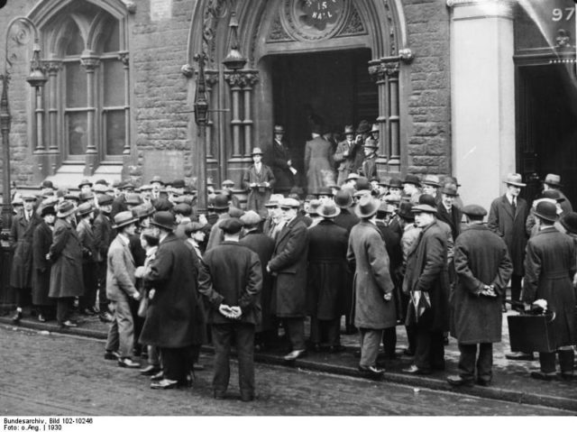 Unemployed men queue outside a workhouse in England, 1930