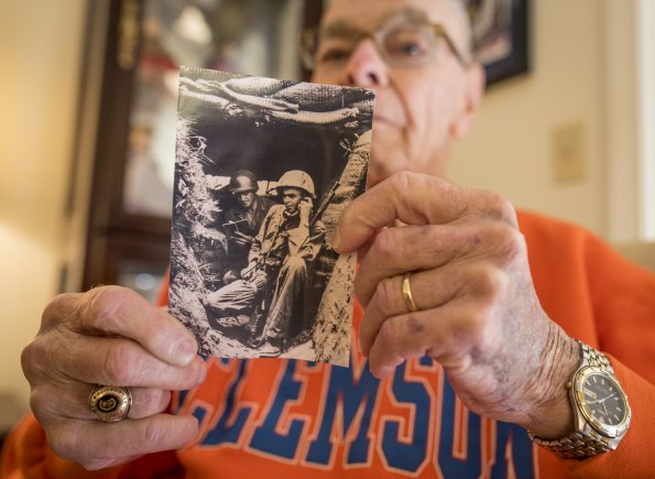 Former U.S. Army 1st Lt. William H. Funchess, 89, who endured 34 months as a prisoner of war during the Korean War, holds a photo of himself in a bunker taken during an engagement in July of 1950 near the Kum River north of Taejon, South Korea, Sept. 21, 2016. "That was my first engagement. There were 13 Russian T-34 tanks across the river firing point-blank into us." Credit: U.S. Army photo by Staff Sgt. Ken Scar.