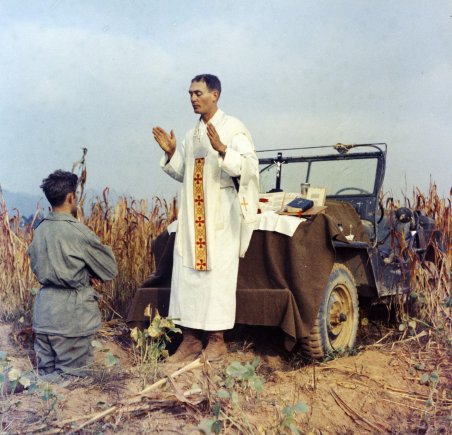 Father Emil Kapaun celebrates Mass using the hood of his jeep as an altar, as his assistant, Patrick J. Schuler, kneels in prayer in Korea on Oct. 7, 1950, less than a month before Kapaun was taken prisoner. Kapaun died in a prisoner of war camp on May 23, 1951, his body wracked by pneumonia and dysentery. On April 11, 2013, President Barack Obama awarded the legendary chaplain, credited with saving hundreds of soldiers during the Korean War, the Medal of Honor posthumously. Credit: Photo by U.S. Army Col. Raymond A. Skeehan.