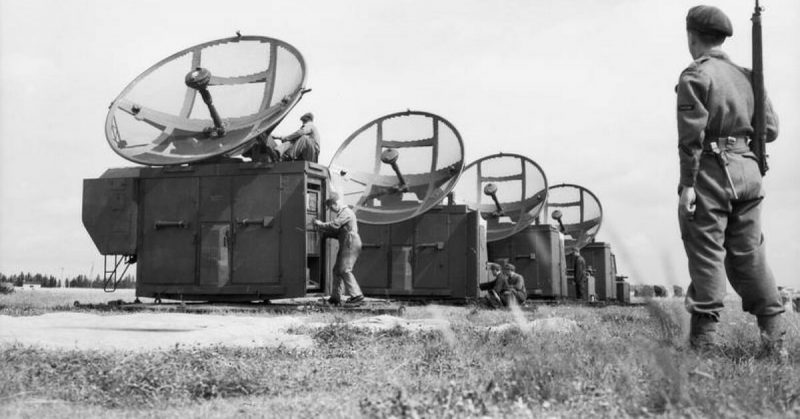 A Royal Air Force Regiment sentry stands guard whilst German technicians assemble captured Mannheim radar equipment at Grove airfield in Denmark.