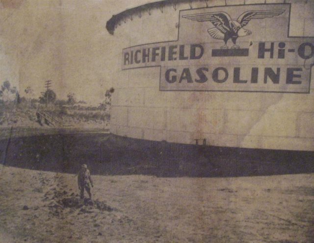 A soldier inspects the crater produced by the near miss that slightly damaged a 14-inch pipeline and dented one of the giant Richfield Oil Company storage tanks. (Los Angeles Examiner Photo)