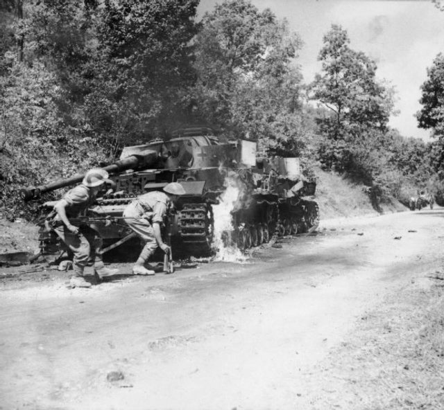 Men of the 2/6th Battalion, Queen’s Royal Regiment (West Surrey) advance past a pair of burning German PzKpfw IV tanks in the Salerno area, 22 September 1943.