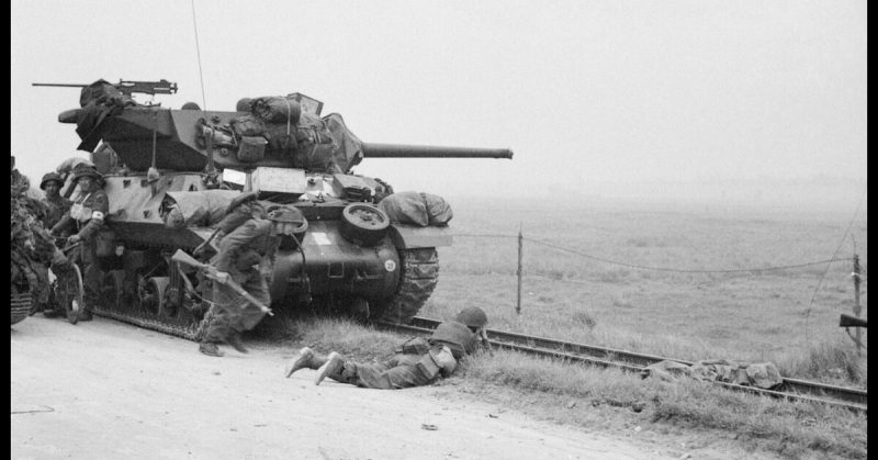 British Forces during the Invasion of Normandy, 6th June 1944 Troops take shelter near an M10 Wolverine tank destroyer.