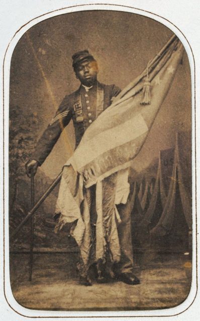 William Harvey Carney with the saved flag, using only a cane after a long recovery;