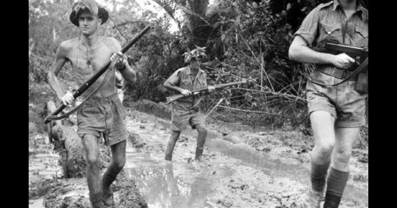 Australian Soldiers run through the thick mud during the Battle of Milne Bay.
