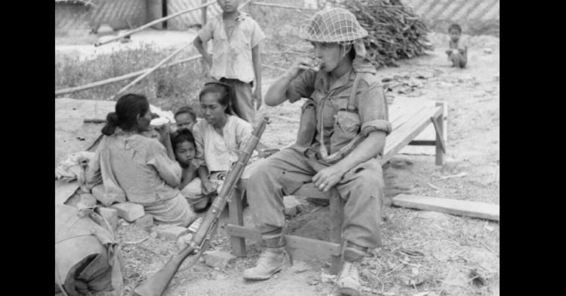 A British soldier in Meiktila sharing tea with a Burmese family