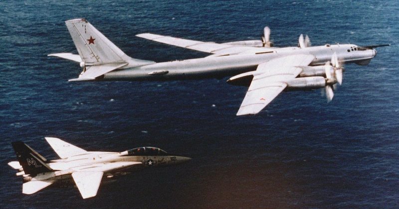 An American F-14 fighter intercepting a Russian Tu-95 long range nuclear bomber.