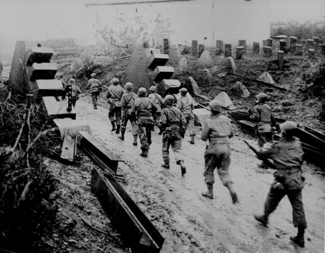 United States Army troops passing through dragon’s teeth on the Siegfried Line in 1944.