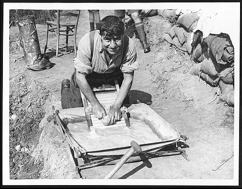 A soldier of the King’s Own Yorkshire Light Infantry washing clothes in an Officer’s canvas bath, Ypres-Comines Canal, 1 October 1917.