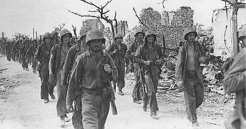 Marines march through the city of Garapan, in Saipan, July 1944.