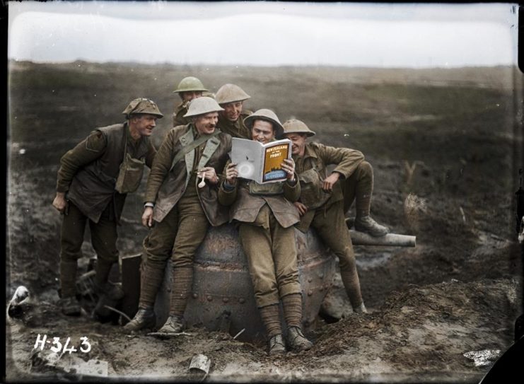The Experience of Trench Warfare Gives Rise to a New Spirit of Independence Amongst Troops of the British Empire. “A group of soldiers from the 3rd Battalion, NZ Rifle Brigade, enjoy the joke of reading a copy of the publication ‘New Zealand at the Front’ while seated on a captured German anti-tank gun.” Photographed by Henry Armytage Bradley Sanders, taken at ‘Clapham Junction’ a muddy part of the battlefield in Belgium on 20 November 1917. Image courtesy of the Alexander Turnball Library. Colourised by Frederic Duriez