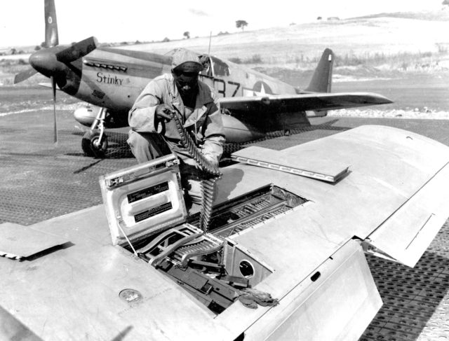 A USAAF armorer of the 100th Fighter Squadron, 332nd Fighter Group, 15th U.S. Air Force checks ammunition belts of the 12.7 mm machine guns in the wings of a North American P-51B Mustang in Italy, ca. September 1944.