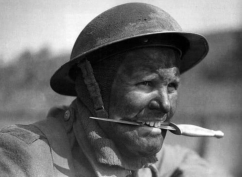 SOE No. 3 Commando holding his fighting knife between his teeth, at Largs in Scotland