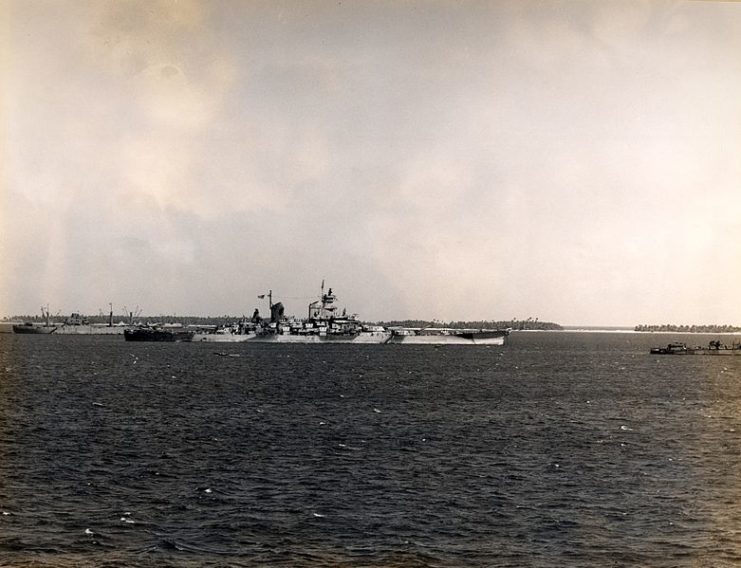 The U.S. Navy battleship USS Iowa at a forward anchorage as viewed from the aircraft carrier USS Intrepid (CV-11). A cargo ship is moored aft of Iowa, and a converted flush deck destroyer ahead. The photo was probably taken at Majuro or Ulithi Atoll. Note Iowa´s camouflage measure 32, design 1B.