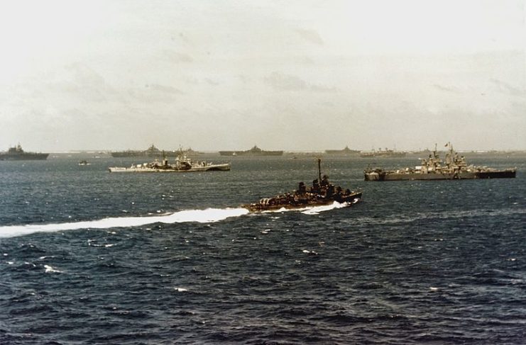 The U.S. Navy destroyer minelayer USS Shannon (DM-25) steams past task forces gathering for the Okinawa Operation at Ulithis Atoll, circa in March 1945.The ships in the near background include the light cruisers USS Flint (CL-97), in left center, and USS Miami (CL-89), at right. Three Essex-class aircraft carriers are anchored in the middle distance. USS Enterprise (CV-6) is at the far left.