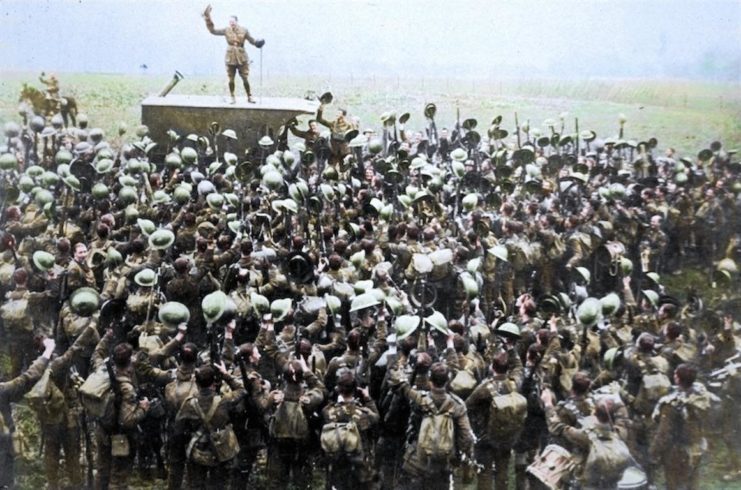 The Commanding Officer of the 9th Battalion, East Surrey Regiment stands on a lorry surrounded by his men and leads a cheer to the King, St Waast, near Bavai, 12 November 1918. Photo colourised by Royston Leonard / mediadrumworld.com