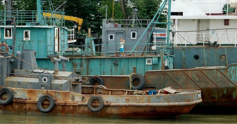 A small North Korean boy appears to wave to the photographer from among dilapidated shipping on the Yalu River in the city of Sinuiju. Photo by ZHart
- CC-BY SA 3.0