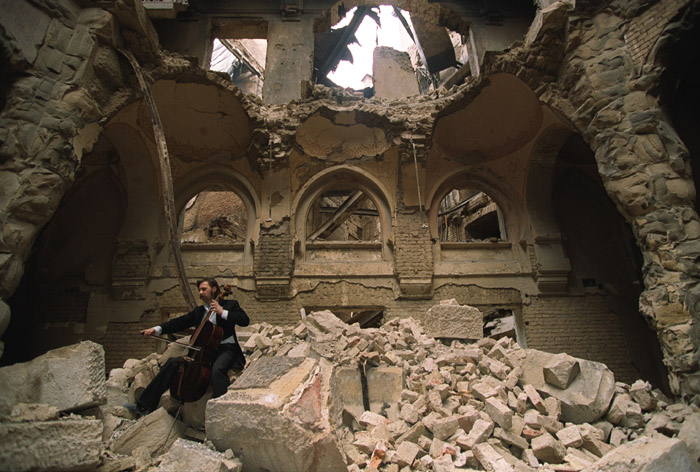 Photo of a local musician, cello player, taken during the war in 1992 in Sarajevo in the partially destroyed National Library. By Mikhail Evstafiev CC BY-SA 3.0