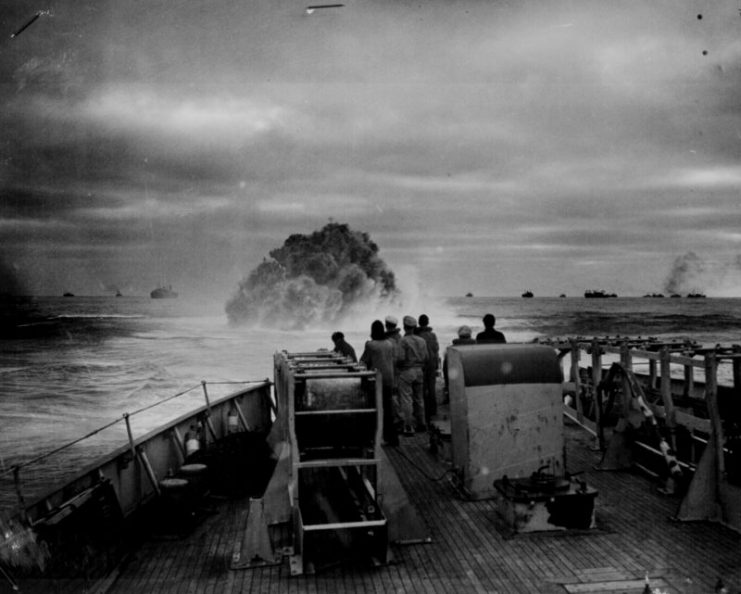 Coast Guardsmen on the deck of the U.S. Coast Guard Cutter Spencer watch the explosion of a depth charge which blasted a Nazi U-boat’s hope of breaking into the center of a large convoy.