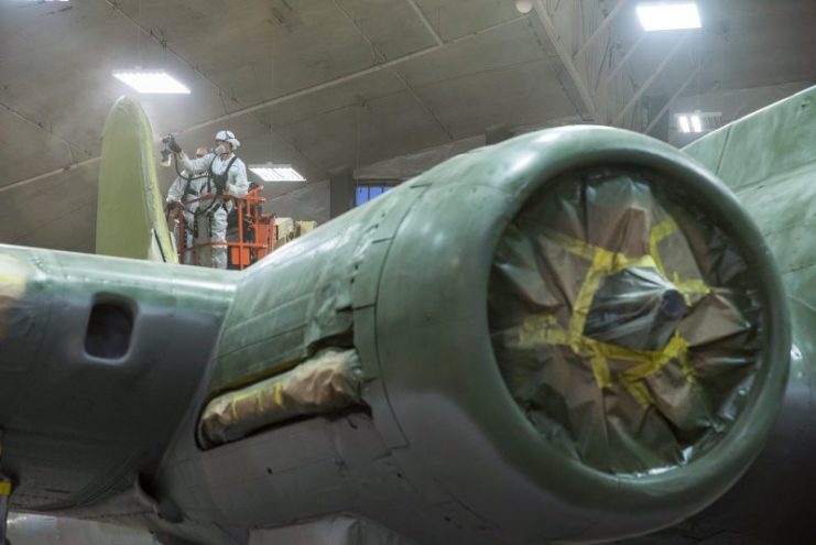 With masking in place on the engine, and exhaust system, among other components, the paint team gets to work on Memphis Belle. (U.S. Air Force photo by Ken LaRock)
