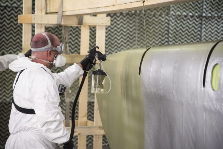 Painting the topcoat over the silver-doped fabric on Memphis Belle’s control surfaces. (U.S. Air Force photo by Ken LaRock)