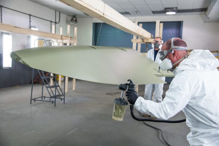 Applying the finishing touches to the olive drab paint on Memphis Belle’s fabric-covered control surfaces. (U.S. Air Force photo by Ken LaRock)