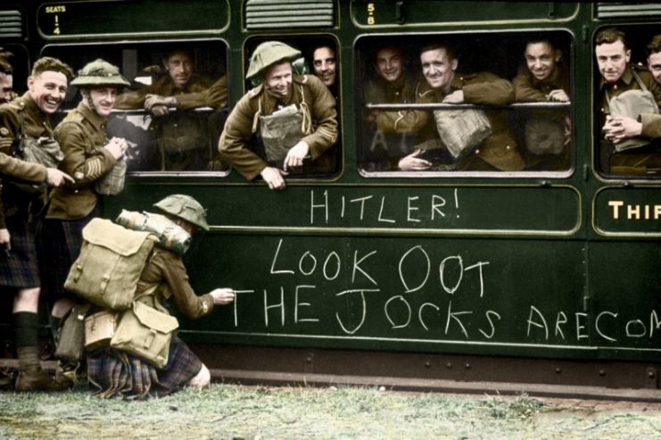 A soldier of the Cameron Highlanders chalks a warning to Hitler on the side of a train as troops leave Aldershot for France. It reads ‘Hitler! Look oot the Jocks are Coming’. Paul Reynolds / mediadrumworld.com
