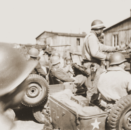 General George S. Patton (seated in the middle jeep) arrives at the newly liberated Ohrdruf concentration camp in the company of a large group of American troops;